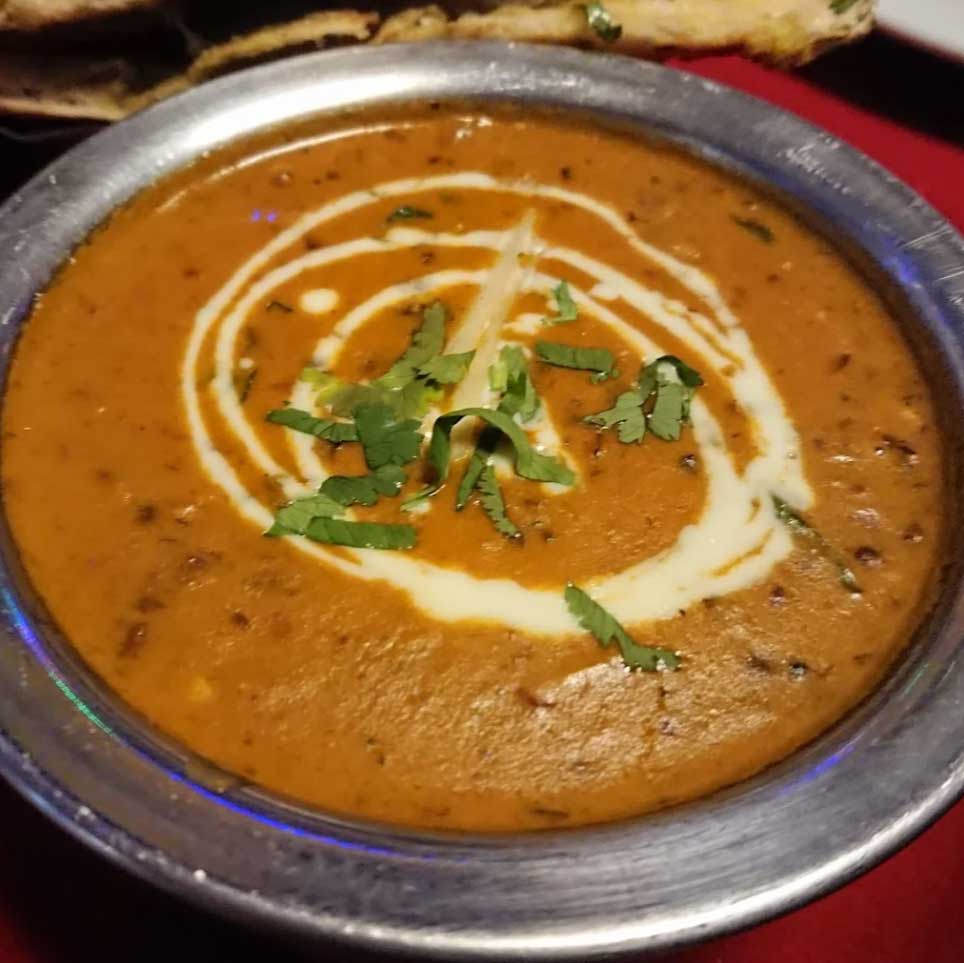 Creamy bowl of dal makhani garnished with a white cream swirl and fresh herbs at The Dine in Broxburn.